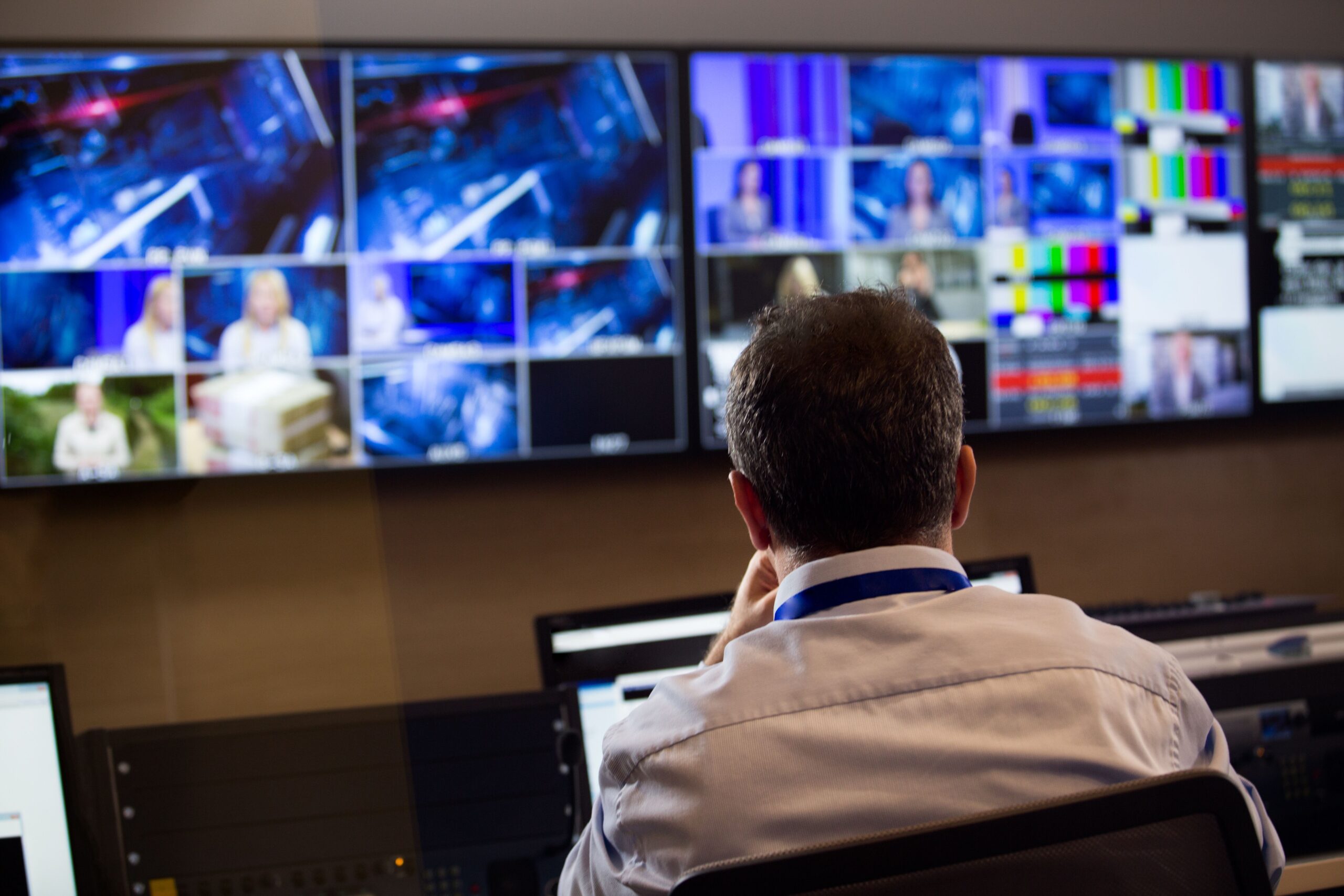 A man seated at a desk, focused on multiple computer monitors displaying various data and information.