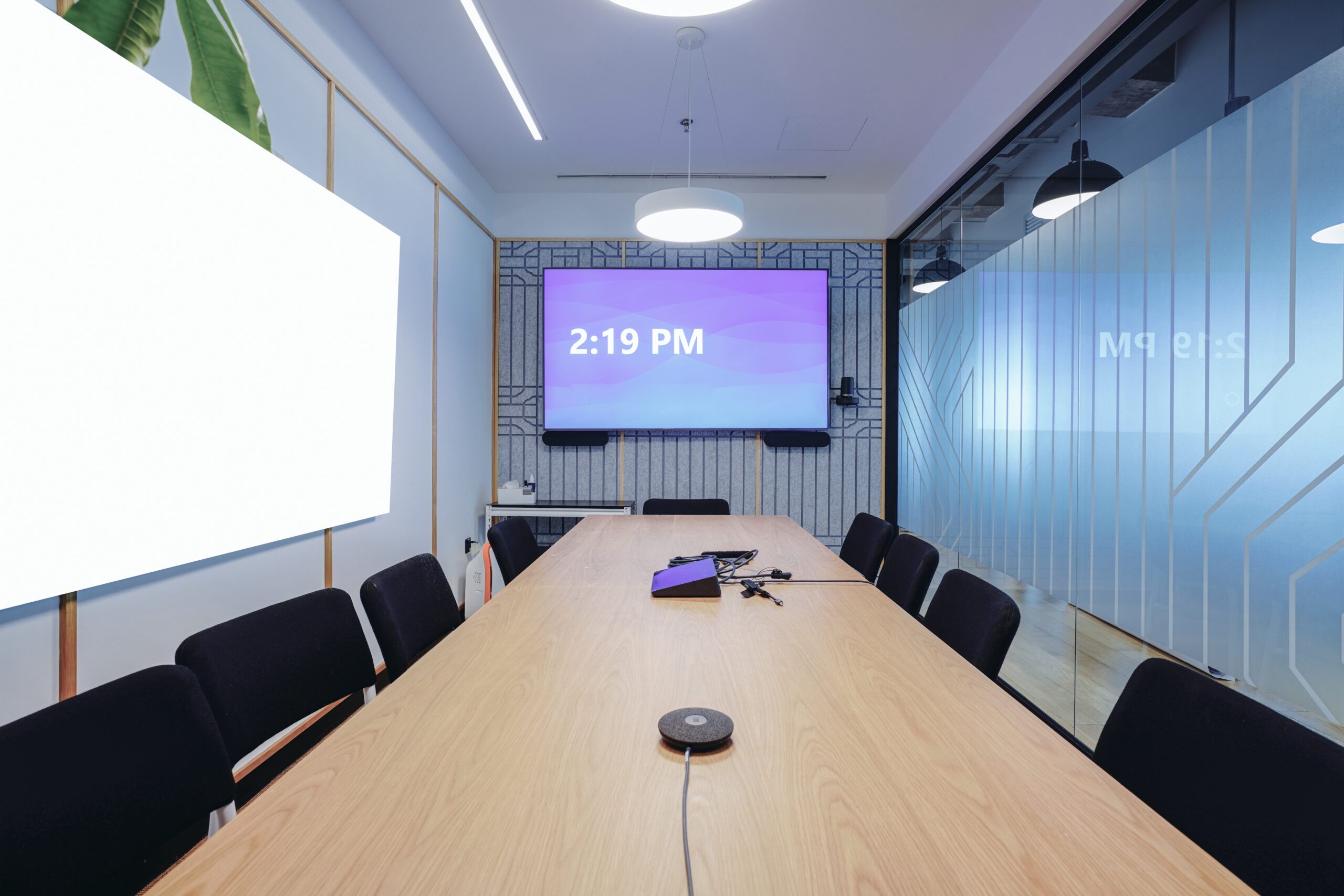 A conference room featuring a large screen at the front and several chairs arranged for attendees.